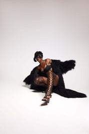 Model wearing Evelyn Mongolian Fur Trench Coat over stylish black outfit, showcasing elegance and luxury.